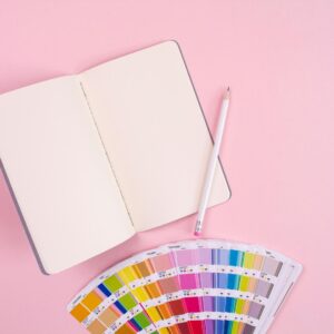 A pencil placed on an open book on a desk, with a variety of colorful cards.