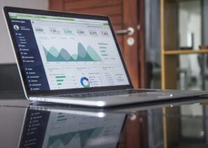 Laptop on a glass top table showing statistics.