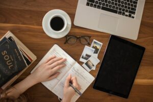 A person writing in a notebook at a desk.